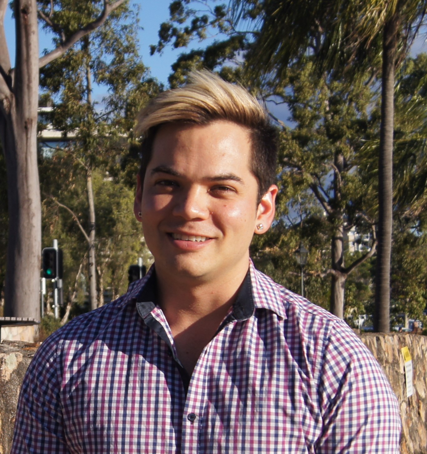 Photo of Robert with a purple, checked shirt outside in front of trees on a sunny day